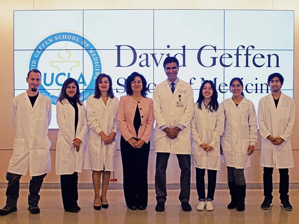 Group in white coats in front of David Geffen School of Medicine screen